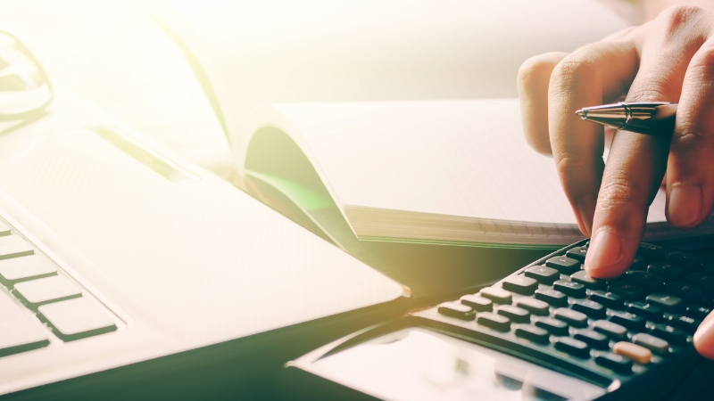 Person calculating costs and planning content strategy for a profitable niche blog website on a work desk