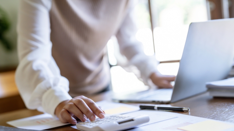 Person working at a desk with a laptop and calculator, focusing on blog revenue and growth planning
