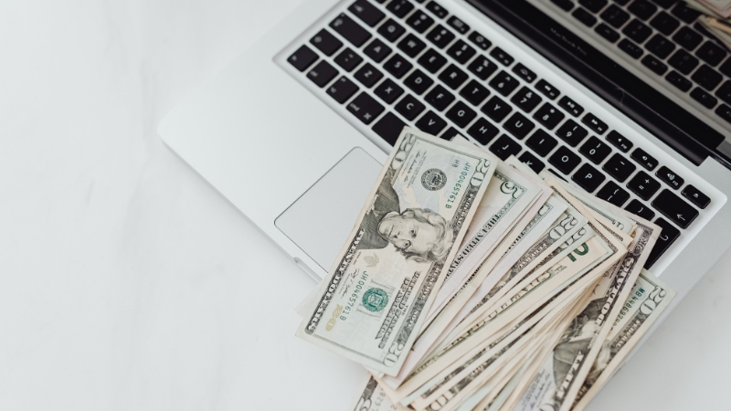 Laptop keyboard with US dollar bills on top