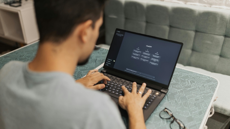 A person types on a laptop with an AI text dashboard open